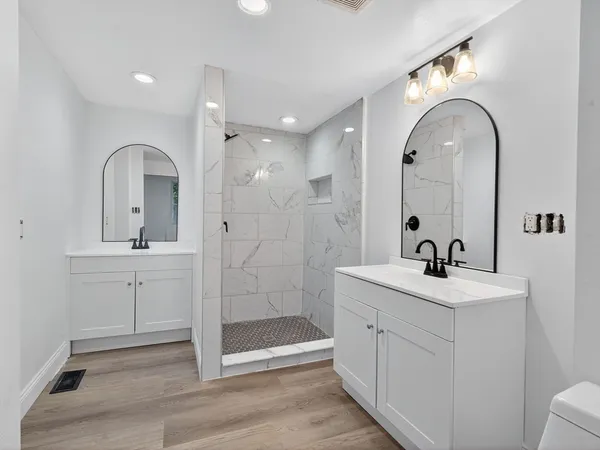 a bathroom with a double vanity sink mirror and shower