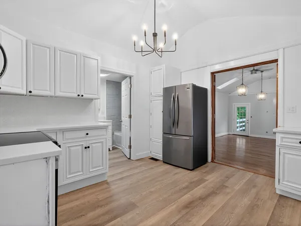 a kitchen with stainless steel appliances granite countertop a refrigerator a sink dishwasher a stove and white cabinets with wooden floor