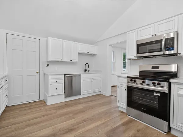a kitchen with stainless steel appliances white cabinets and a stove top oven