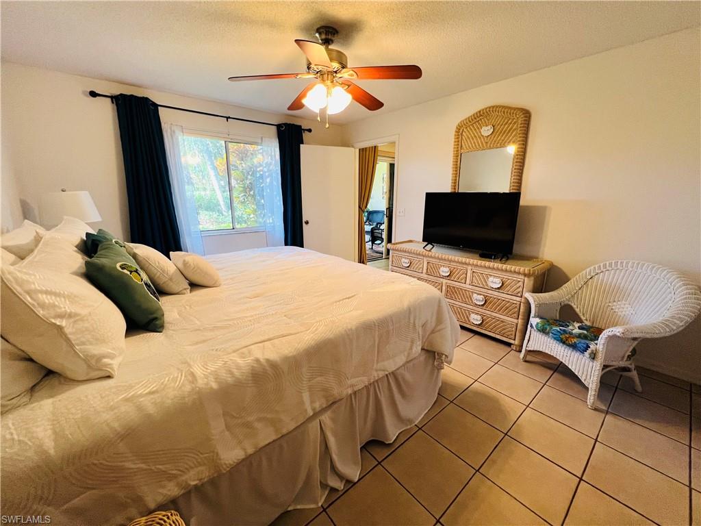 7719 Jewel Lane, Unit 103 Naples, FL 34109 - Photo 11 of 16 a bedroom with a bed and a flat screen tv
