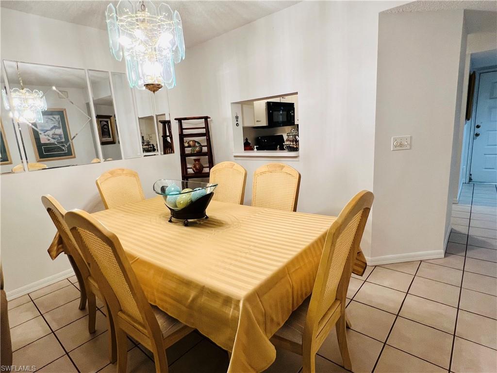7719 Jewel Lane, Unit 103 Naples, FL 34109 - Photo 6 of 16 a dining room with furniture and chandelier