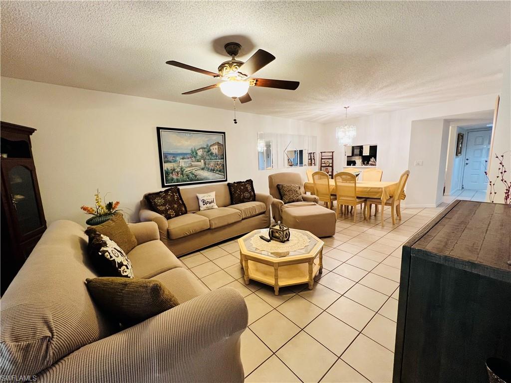 7719 Jewel Lane, Unit 103 Naples, FL 34109 - Photo 9 of 16 a living room with couches a coffee table and a lamp with wooden floor