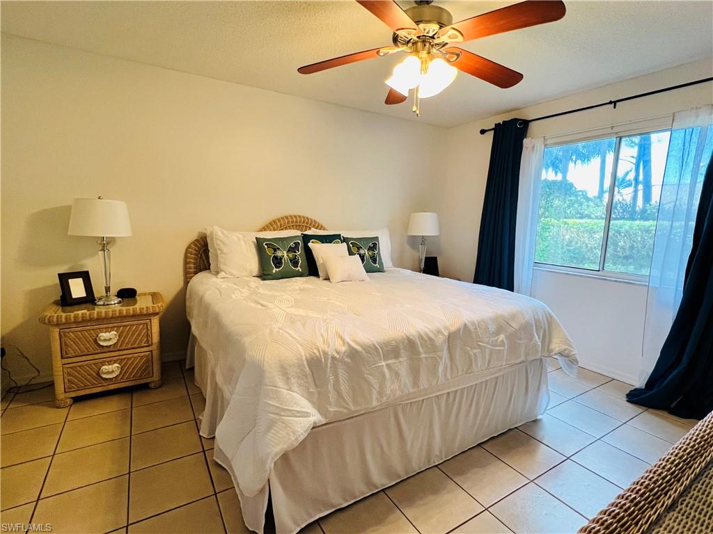 7719 Jewel Lane, Unit 103 Naples, FL 34109 - Photo 10 of 16 a bedroom with a bed and a chandelier