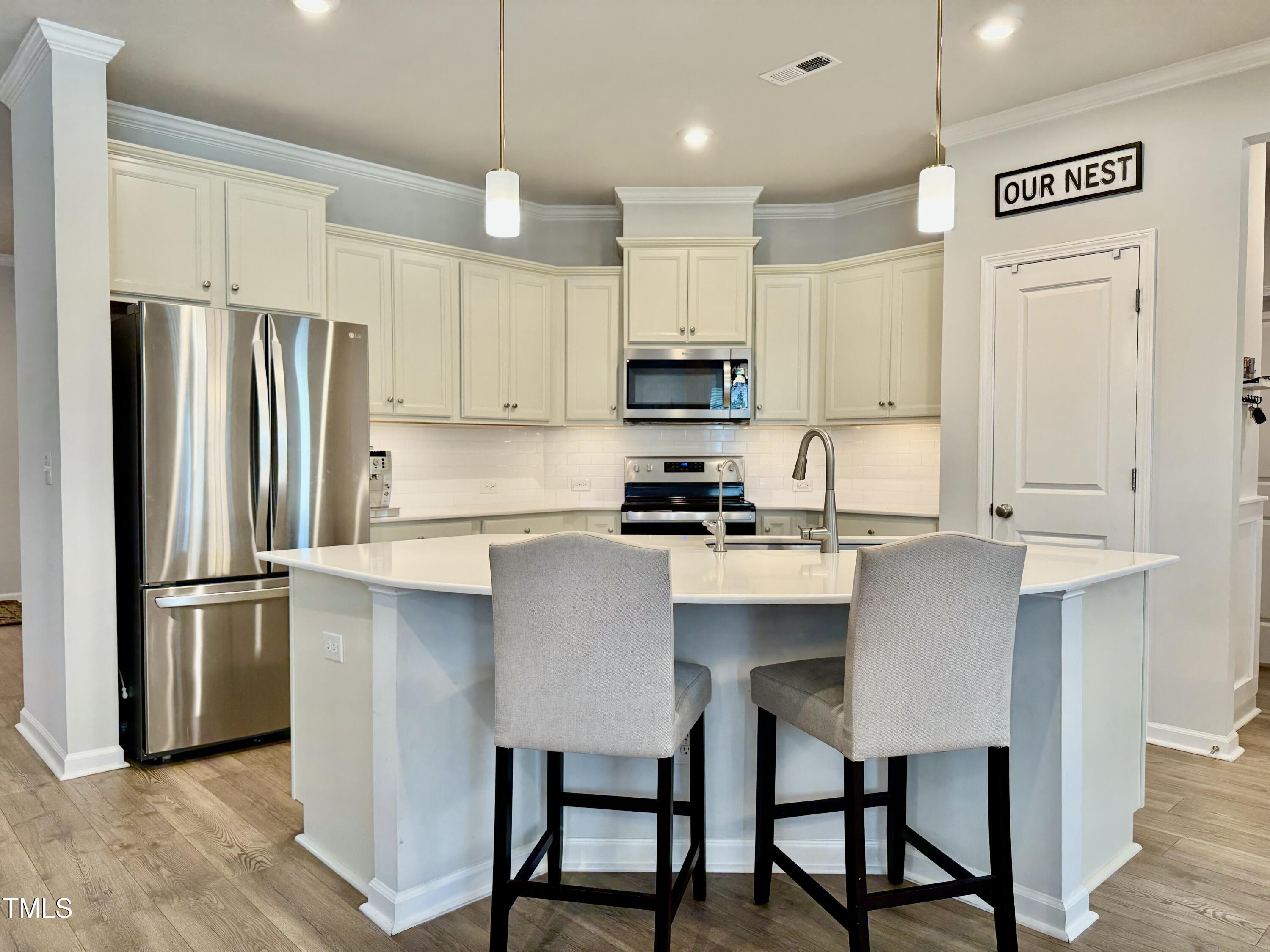 8600 Deep Elm Drive Wake Forest, NC 27587 - Photo 7 of 21 a kitchen with stainless steel appliances a refrigerator a stove a sink and white cabinets with wooden floor