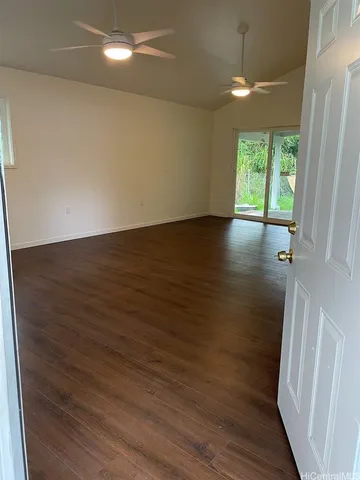 an empty room with wooden floor and windows with curtains
