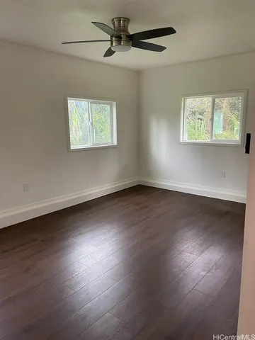 an empty room with wooden floor fan and windows