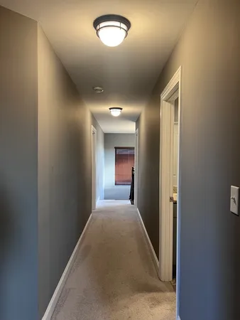 a view of a hallway with windows and chandelier
