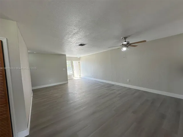 an empty room with wooden floor and chandelier fan