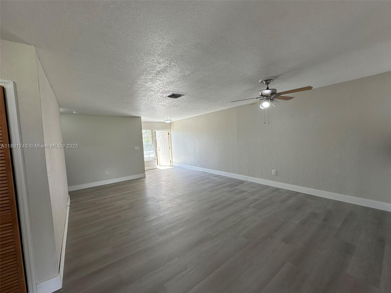 3611 Northwest 194th Terrace Miami Gardens, FL 33056 - Photo 4 of 15 an empty room with wooden floor and chandelier fan