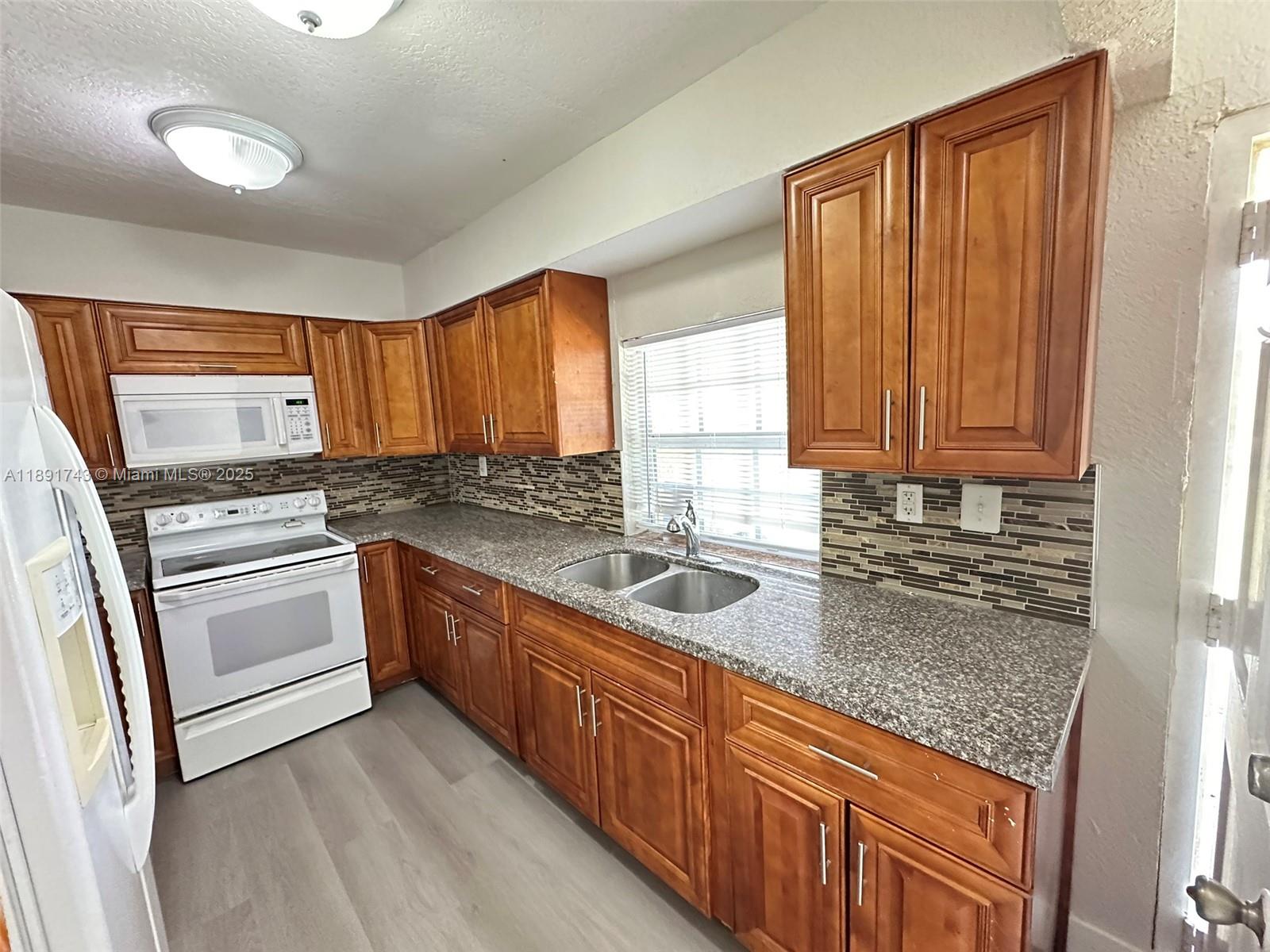 3611 Northwest 194th Terrace Miami Gardens, FL 33056 - Photo 7 of 15 a kitchen with granite countertop stainless steel appliances a stove sink and cabinets