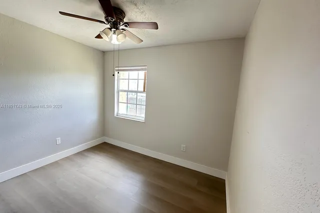 an empty room with a window and a fan