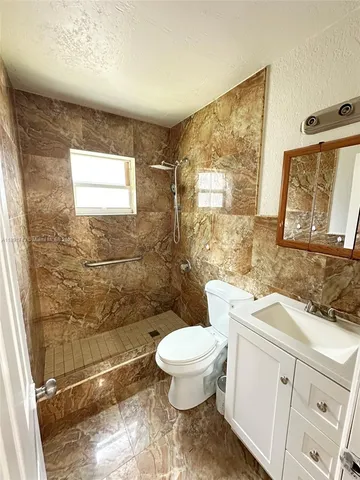 a bathroom with a granite countertop toilet a sink and a mirror