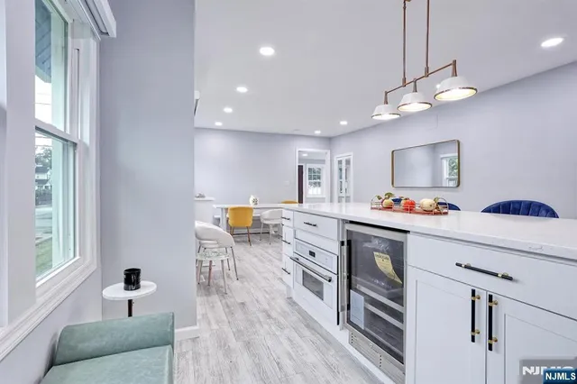 a kitchen with a sink dishwasher a dining table and chairs with wooden floor
