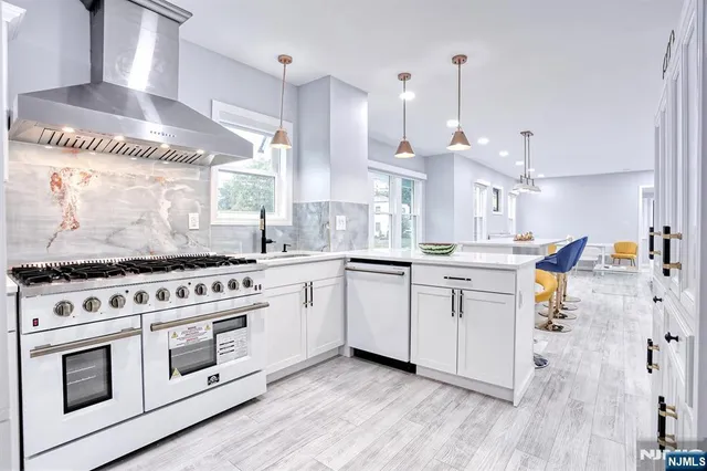a kitchen with stainless steel appliances a stove a sink and white cabinets with wooden floor