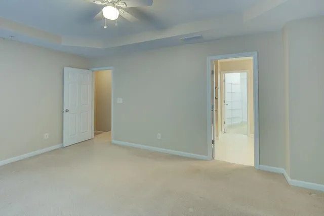 an empty room with windows and ceiling fan