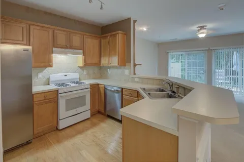 a kitchen that has a sink a stove and chairs