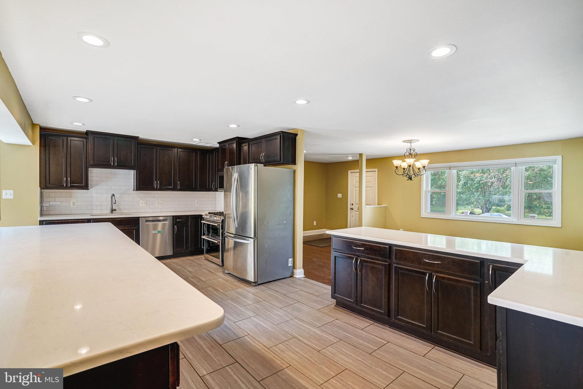 5227 Cather Road Springfield, VA 22151 - Photo 15 of 72 a large kitchen with stainless steel appliances a large counter top a stove a chimney a sink and a refrigerator