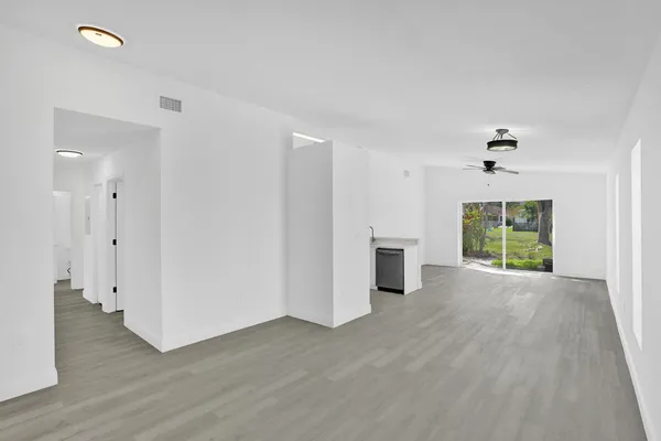 an empty room with wooden floor a ceiling fan and windows