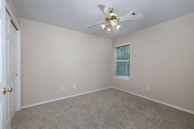 an empty room with a chandelier fan and windows