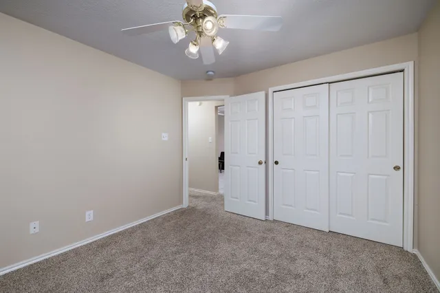 a view of an empty room and chandelier fan