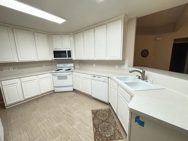 a kitchen with a sink white cabinets and white appliances