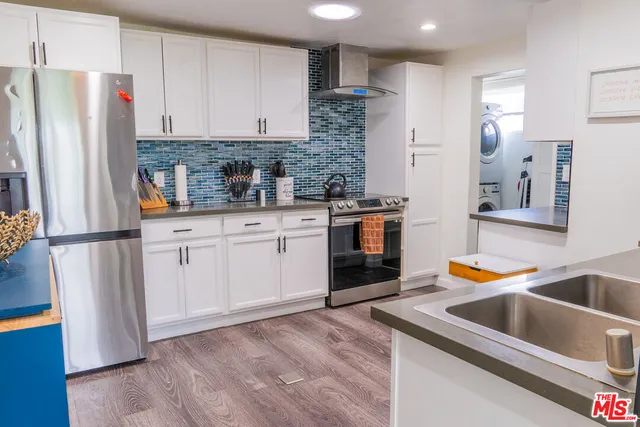 a kitchen with stainless steel appliances granite countertop a refrigerator a stove and a sink