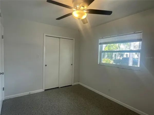 an empty room with a window and a fan
