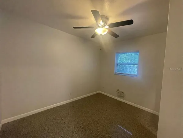 an empty room with a chandelier fan and windows