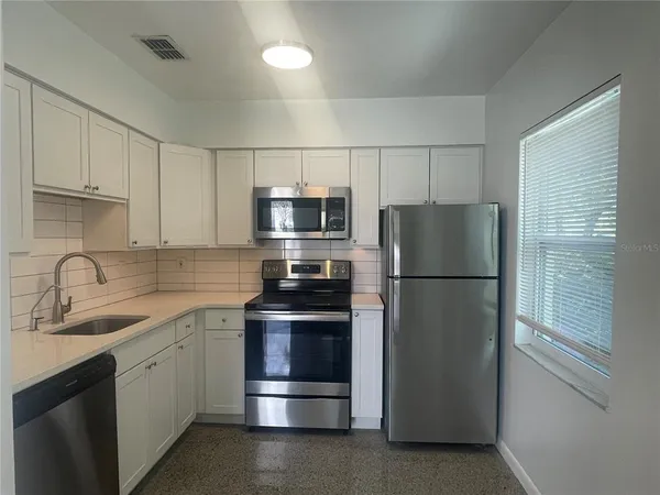 a kitchen with stainless steel appliances a refrigerator sink and cabinets