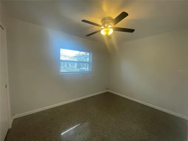 an empty room with windows and fan