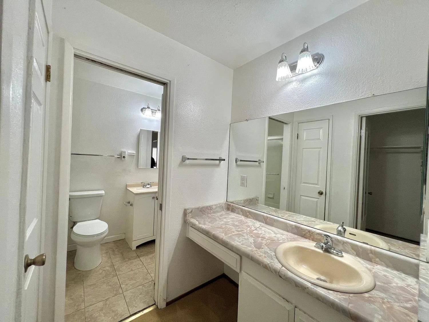 80 East Portola Way, Unit 105 Tracy, CA 95376 - Photo 11 of 12 a bathroom with a granite countertop sink a toilet a mirror and shower