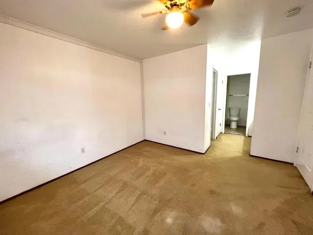 an empty room with a chandelier fan and windows