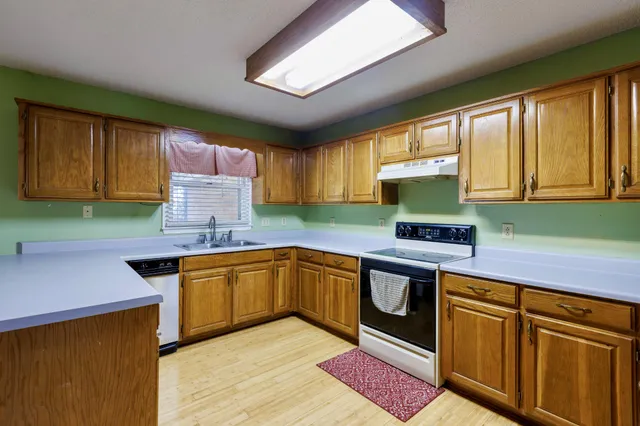 a kitchen with stainless steel appliances granite countertop wooden cabinets a sink and dishwasher a stove with wooden floor