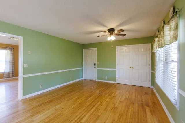 a view of an empty room with window and wooden floor