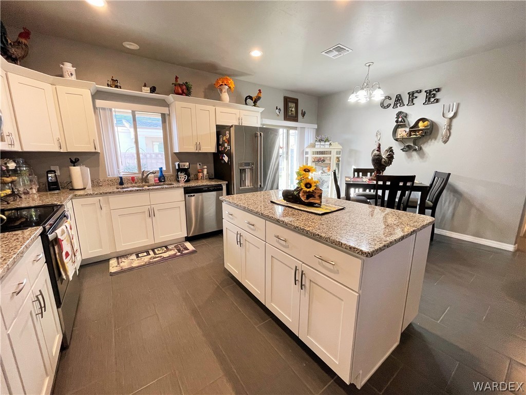 3605 North Kenneth Road Kingman, AZ 86409 - Photo 12 of 28 a kitchen with stainless steel appliances granite countertop a stove top oven a sink a refrigerator white cabinets and wooden floor