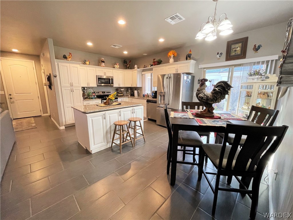 3605 North Kenneth Road Kingman, AZ 86409 - Photo 8 of 28 a kitchen with stainless steel appliances kitchen island granite countertop a dining table chairs and a refrigerator