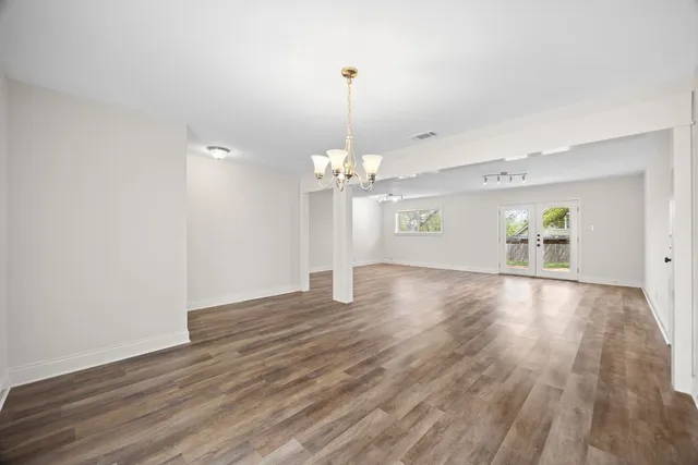 a view of a room with wooden floor chandelier and windows