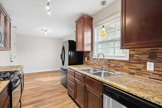 a kitchen with granite countertop a sink stove and refrigerator