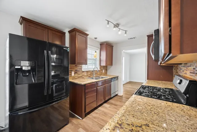 a kitchen with stainless steel appliances granite countertop a refrigerator and a stove