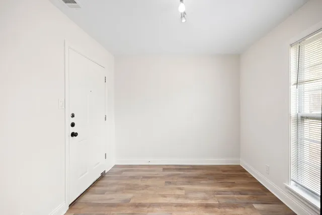 a view of an empty room with wooden floor and a window