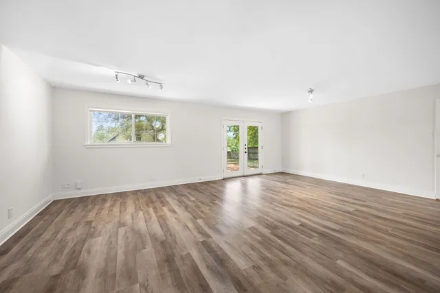 an empty room with wooden floor and window
