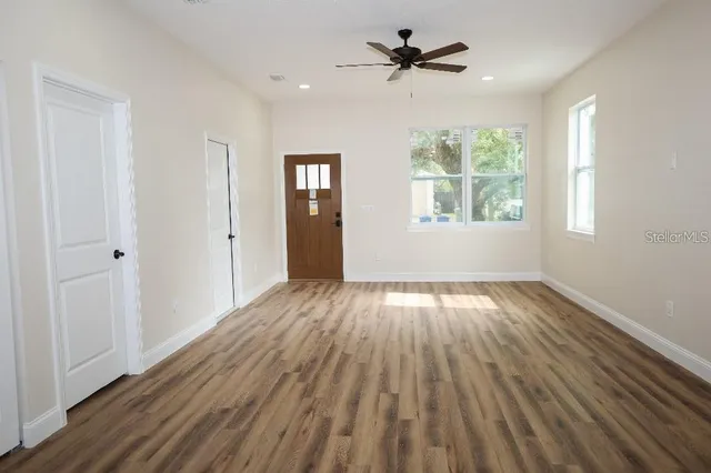 a view of empty room with wooden floor and fan
