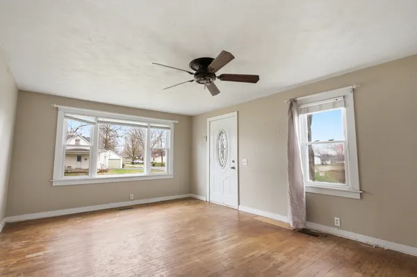 a view of an empty room with wooden floor and a window