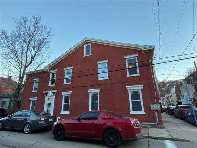 a red car parked in front of a brick building