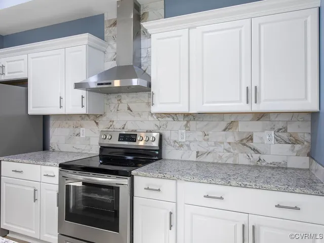 a kitchen with stainless steel appliances granite countertop white cabinets and a stove