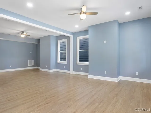 an empty room with wooden floor and windows
