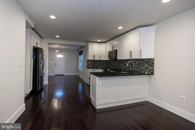 a view of kitchen with stainless steel appliances granite countertop a stove a sink and a refrigerator with wooden floor