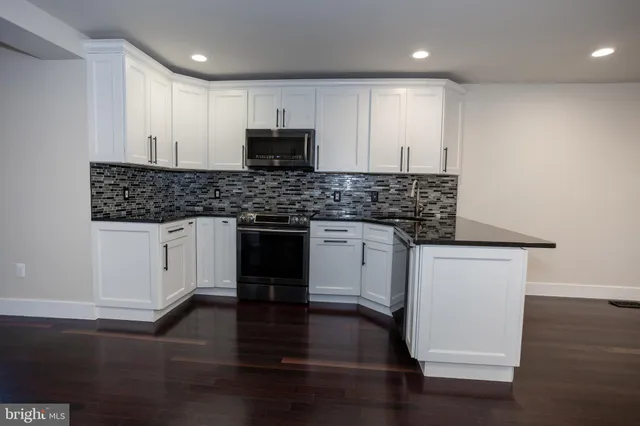 a kitchen with stainless steel appliances granite countertop a stove a sink and a microwave