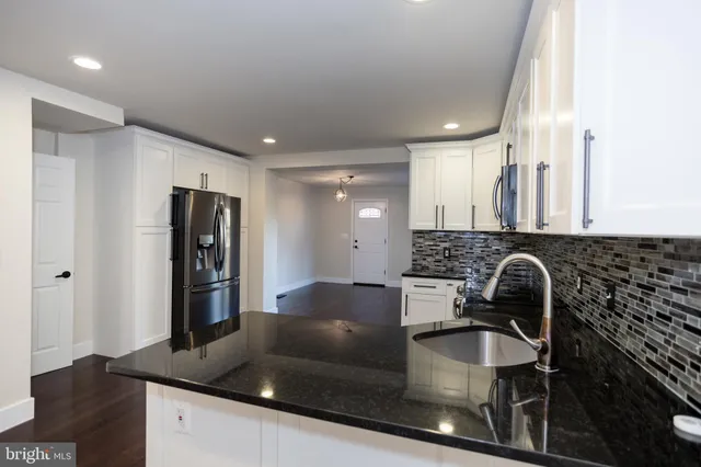 a kitchen with granite countertop a sink and a stove top oven with wooden floor