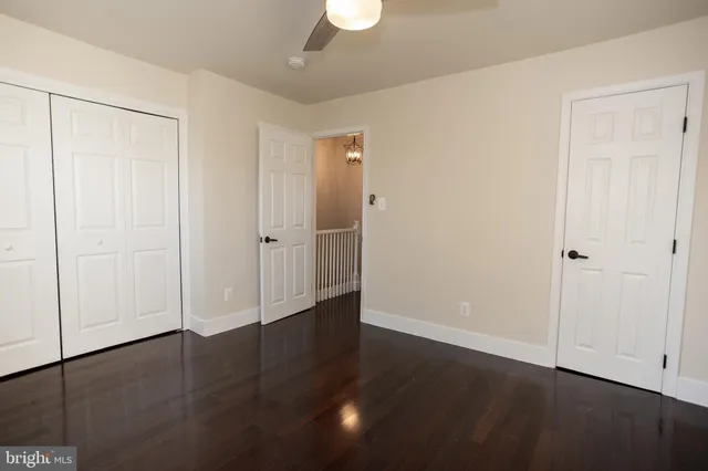 an empty room with wooden floor cabinet and windows